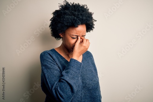 Young beautiful African American afro woman with curly hair wearing casual sweater tired rubbing nose and eyes feeling fatigue and headache. Stress and frustration concept. © Krakenimages.com