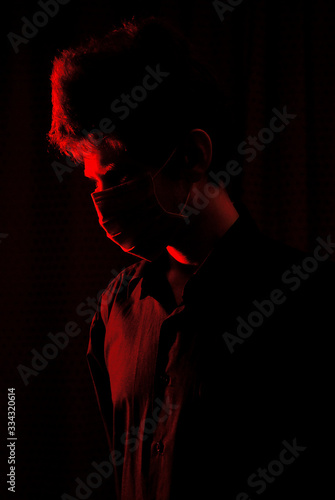 masked doctor in a dark room with red light © maxfalko