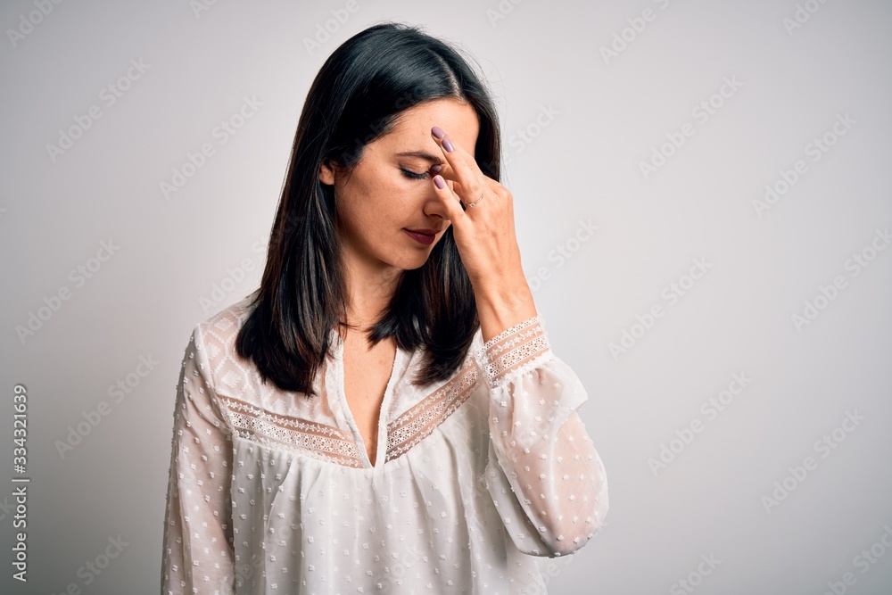 Young brunette woman with blue eyes wearing casual t-shirt over isolated white background tired rubbing nose and eyes feeling fatigue and headache. Stress and frustration concept. Young brunette woman with blue eyes wearing casual t-shirt over isolated white background tired rubbing nose and eyes feeling fatigue and headache. Stress and frustration concept.