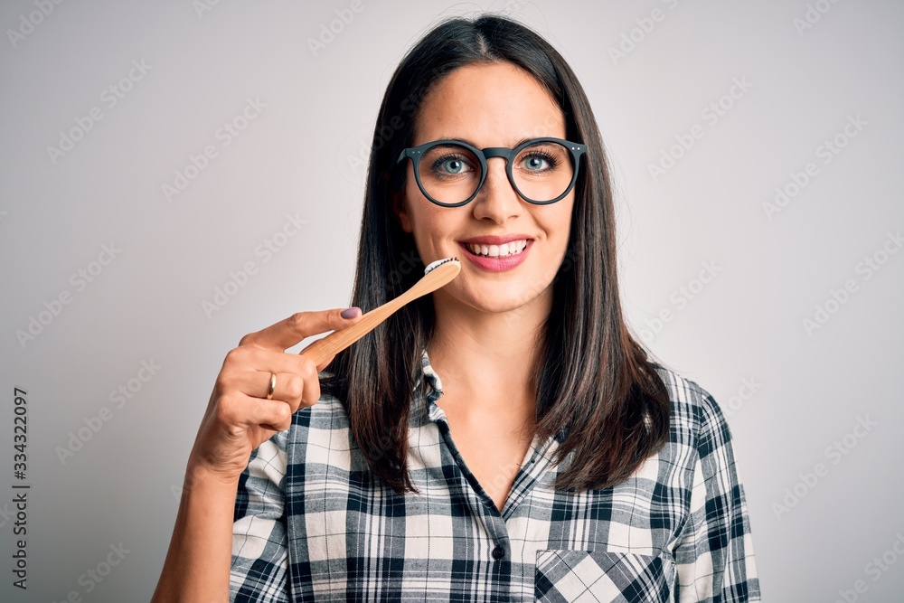 Young caucasian woman wearing glasses brushing her teeth using tooth brush and oral paste, cleaning teeth and tongue as healthy health care morning routine Young caucasian woman wearing glasses brushing her teeth using tooth brush and oral paste, cleaning teeth and tongue as healthy health care morning routine