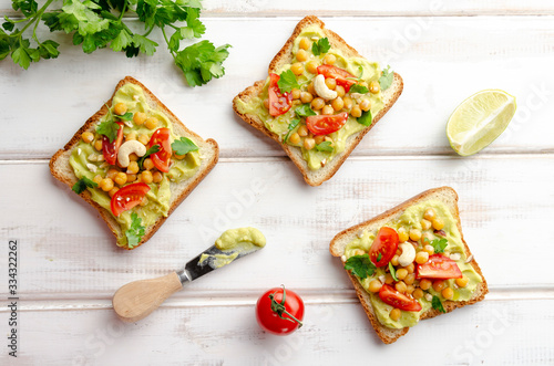 Vegan sandwich with avocado, nuts, vegetables and olive oil on white wooden table