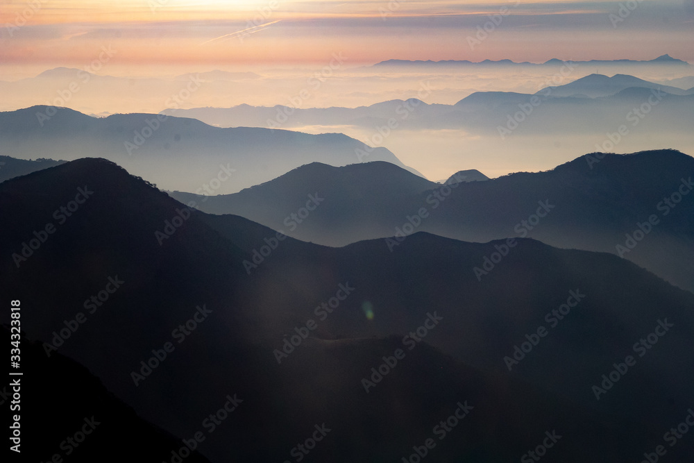 Atardecer amanecer en paisaje con siluetas de montañas, bruma y nubes