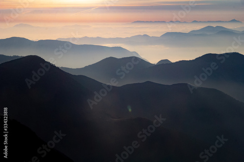 Atardecer amanecer en paisaje con siluetas de montañas, bruma y nubes