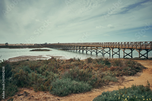 Quinta do Lago view in Algarve, Portugal. Wooden bridge along the river and blue sky with clouds