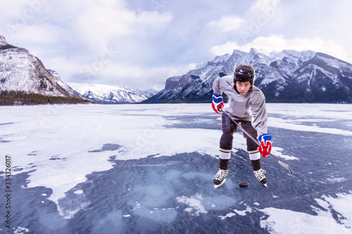 Canvas Print Junior Ice hockey player in outdoor action surrounded by mountains