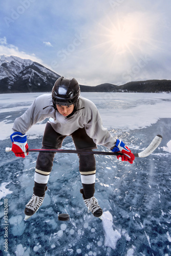 Junior Ice hockey player in outdoor action surrounded by mountains