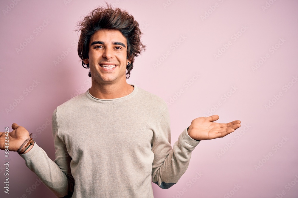 Young handsome man wearing casual t-shirt standing over isolated pink background smiling showing both hands open palms, presenting and advertising comparison and balance Young handsome man wearing casual t-shirt standing over isolated pink background smiling showing both hands open palms, presenting and advertising comparison and balance
