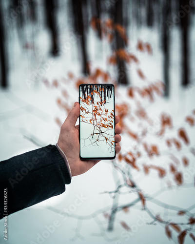 Man holding cellphone in snowy forrest