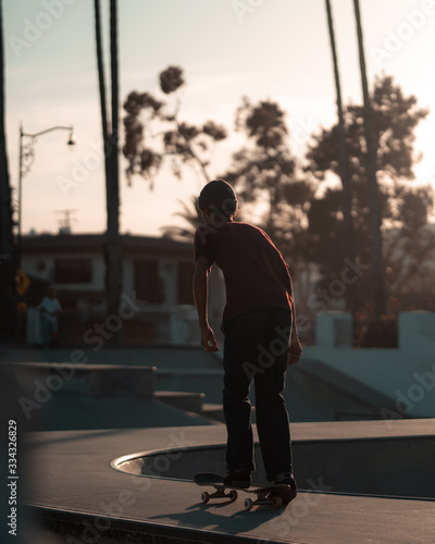 Young man skateboarding through californian skatepark in sunset