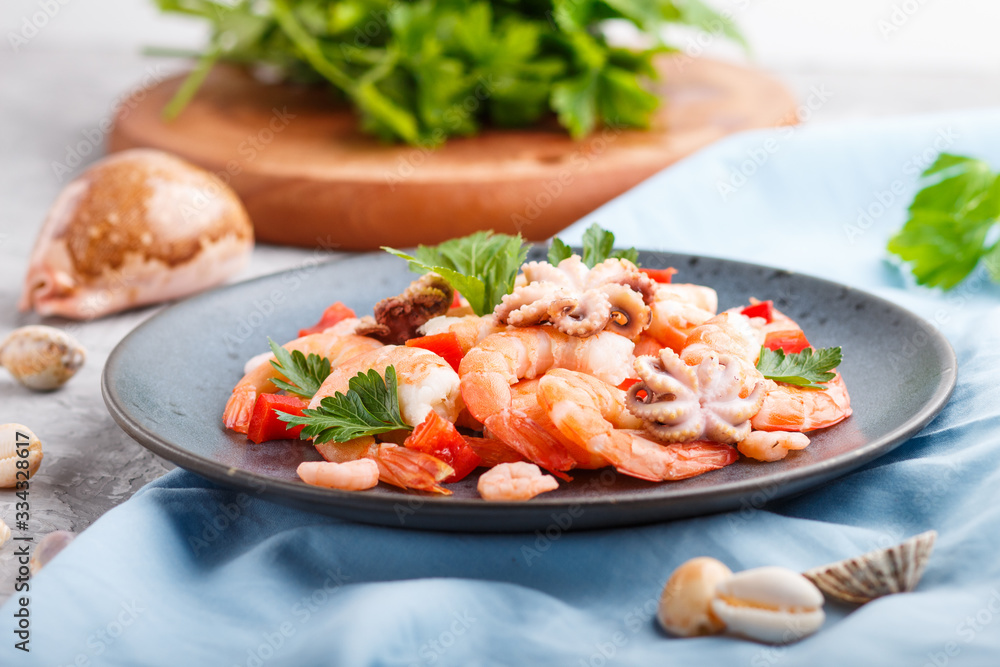 Boiled shrimps or prawns and small octopuses with herbs on a blue ceramic plate on a gray concrete background. Side view, selective focus. Boiled shrimps or prawns and small octopuses with herbs on a blue ceramic plate on a gray concrete background. Side view, selective focus.
