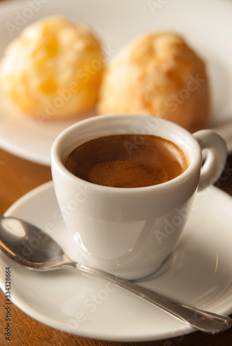 cup of espresso coffee viewed from the front with cheese breads in the background