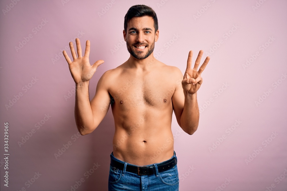 Young handsome strong man with beard shirtless standing over isolated pink background showing and pointing up with fingers number eight while smiling confident and happy.