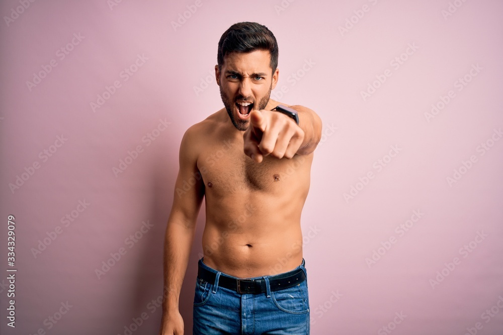 Fototapeta premium Young handsome strong man with beard shirtless standing over isolated pink background pointing displeased and frustrated to the camera, angry and furious with you