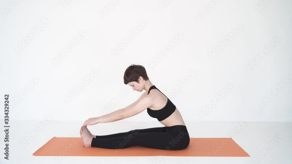Young woman practicing yoga paschimottanasana forward bend in white studio Young woman practicing yoga paschimottanasana forward bend in white studio