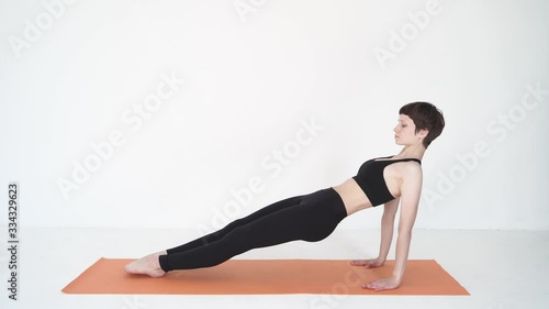 Young woman doing yoga bridge pose purvottanasana in white studio photo
