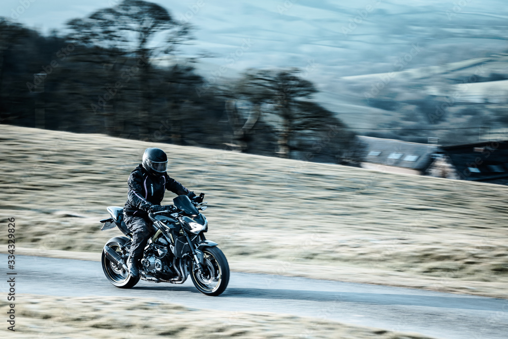 Biker Riding Sport Motorcycle on Rural Road Biker Riding Sport Motorcycle on Rural Road