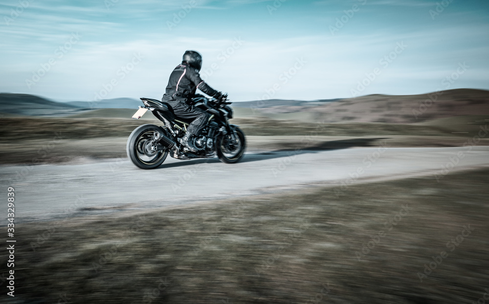 Fototapeta premium Biker Riding Sport Motorcycle on Rural Road