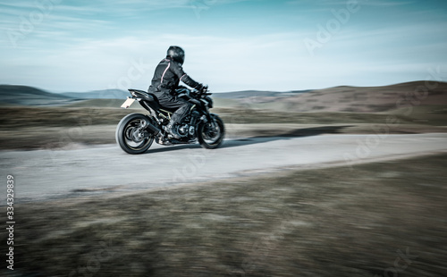 Fototapeta Naklejka Na Ścianę i Meble -  Biker Riding Sport Motorcycle on Rural Road