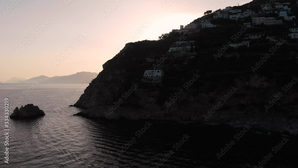 Aerial drone tracking shot from behind silhouette cliffs to the sea and sunset Aerial drone tracking shot from behind silhouette cliffs to the sea and sunset