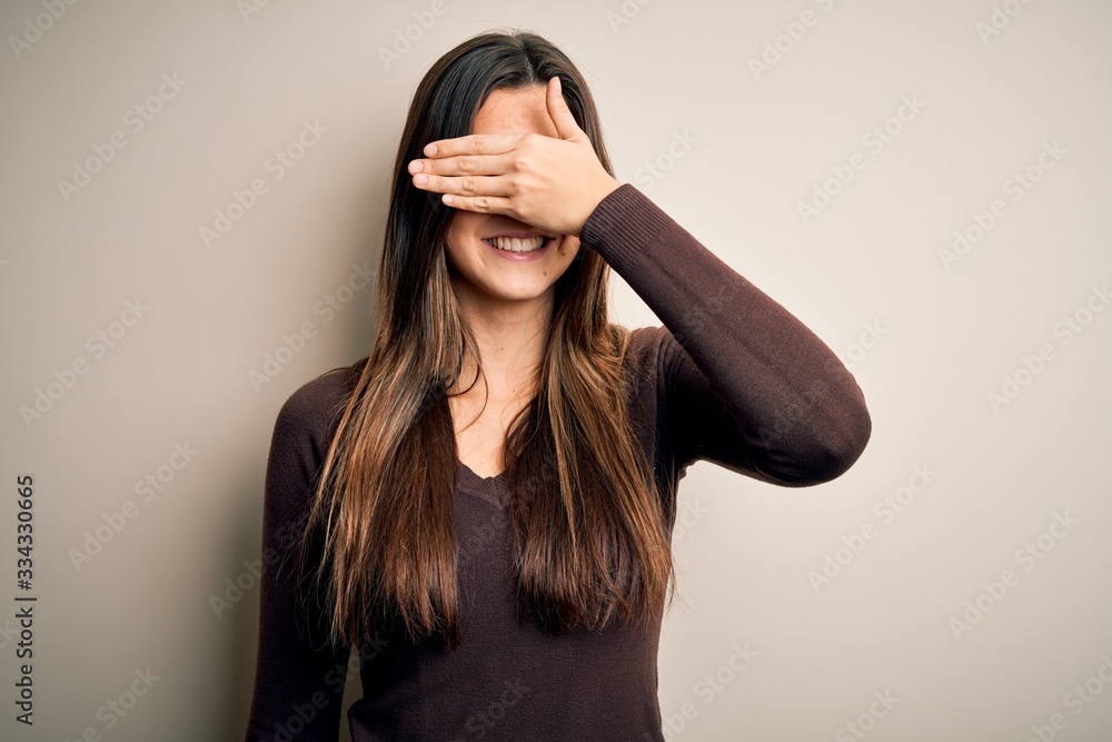 Young beautiful girl wearing casual sweater standing over isolated white background smiling and laughing with hand on face covering eyes for surprise. Blind concept. Young beautiful girl wearing casual sweater standing over isolated white background smiling and laughing with hand on face covering eyes for surprise. Blind concept.