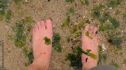 Bare human feet waves bringing seaweed particles to the shore, slow motion from 120 fps footage photo