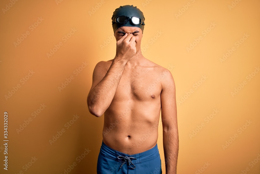 Young handsome man shirtless wearing swimsuit and swim cap over isolated yellow background tired rubbing nose and eyes feeling fatigue and headache. Stress and frustration concept.