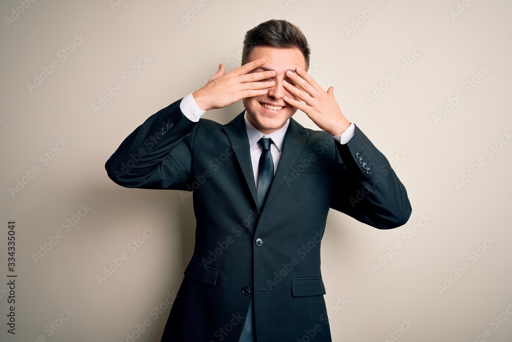 Young handsome business man wearing elegant suit and tie over isolated background covering eyes with hands smiling cheerful and funny. Blind concept. Young handsome business man wearing elegant suit and tie over isolated background covering eyes with hands smiling cheerful and funny. Blind concept.
