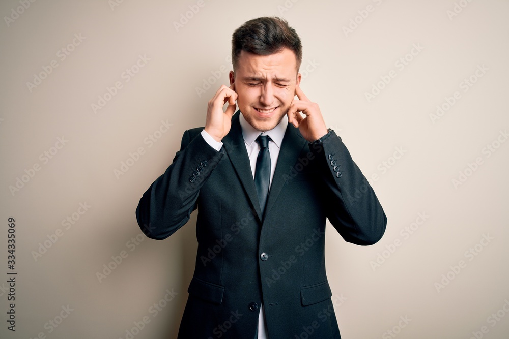 Young handsome business man wearing elegant suit and tie over isolated background covering ears with fingers with annoyed expression for the noise of loud music. Deaf concept. Young handsome business man wearing elegant suit and tie over isolated background covering ears with fingers with annoyed expression for the noise of loud music. Deaf concept.