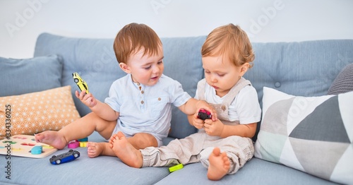 Beautiful toddlers sitting on the sofa playing with toys at home
