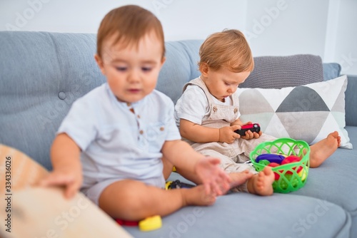 Beautiful toddlers sitting on the sofa playing with toys at home