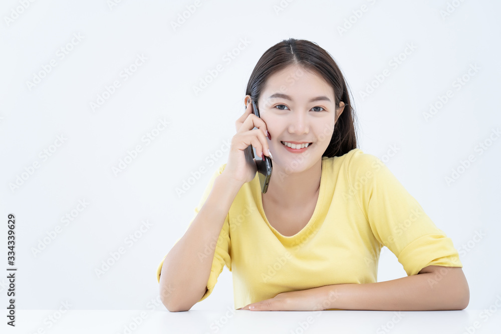 Asian young woman ware yellow t-shirt using talking mobile phone or smart phone in white office room background Asian young woman ware yellow t-shirt using talking mobile phone or smart phone in white office room background