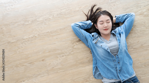 Attractive Asian young woman relax and happy sweet dream sleeping resting on oak wooden floor with copy space from flat lay top view
