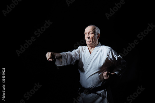Old athlete beats punches arms on a black background