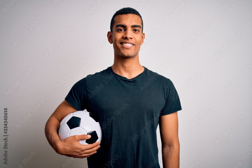 Φωτογραφία Handsome african american man playing footbal holding soccer ball over white background with a happy and cool smile on face