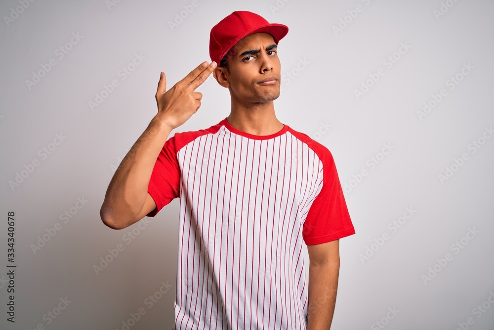 Young handsome african american sportsman wearing striped baseball t-shirt and cap Shooting and killing oneself pointing hand and fingers to head like gun, suicide gesture.