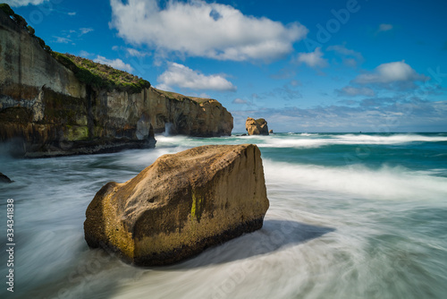 Tableau sur toile Rock formations surrounded by ocean waves breaking against the rocky landscape o