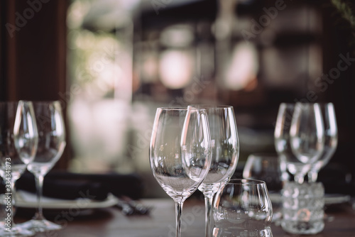 Decorated restaurant table setting prepared for fine dining with empty wine glasses, plate and cutlery and other decor. 