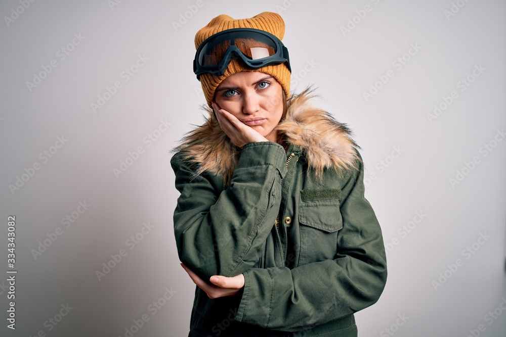 Young beautiful skier woman with blue eyes wearing snow sportswear and ski goggles thinking looking tired and bored with depression problems with crossed arms. Young beautiful skier woman with blue eyes wearing snow sportswear and ski goggles thinking looking tired and bored with depression problems with crossed arms.