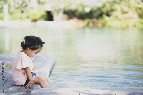 Fototapeta Naklejka Na Ścianę i Meble -  Little girl sitting at the swimming pool outdoor.