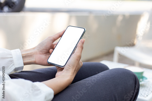 cell phone Mockup image blank white screen.woman hand holding texting using mobile on desk at coffee shop.background empty space for advertise text.people contact marketing business,technology