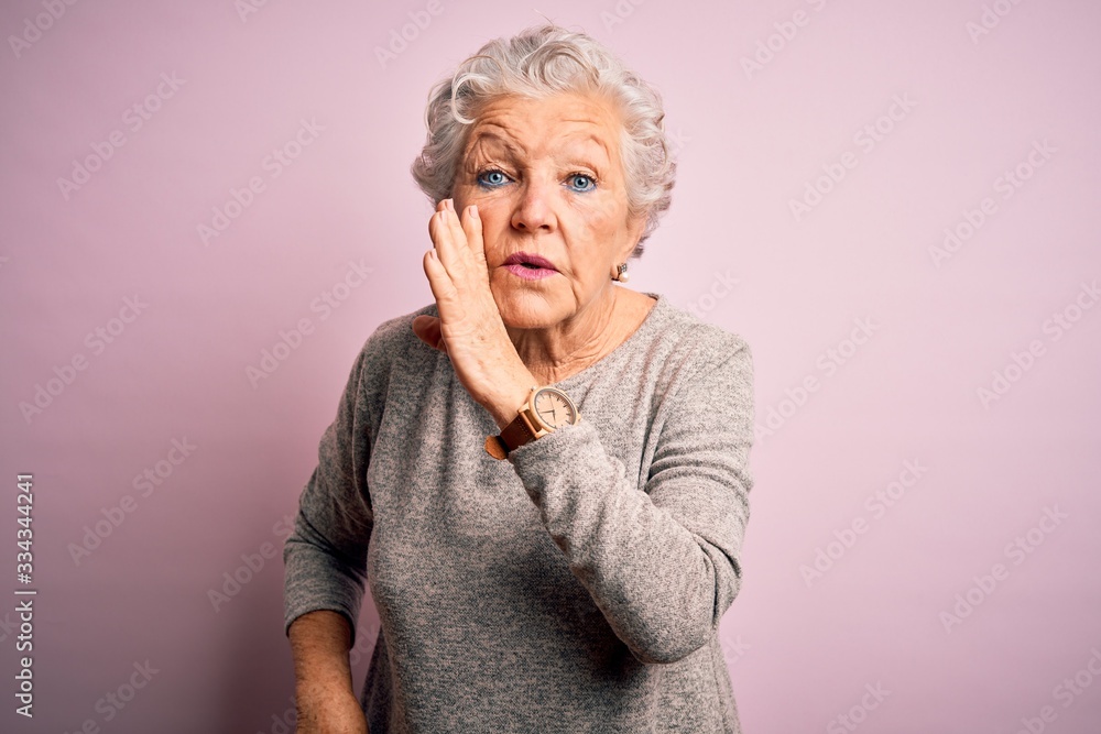 Senior beautiful woman wearing casual t-shirt standing over isolated pink background hand on mouth telling secret rumor, whispering malicious talk conversation Senior beautiful woman wearing casual t-shirt standing over isolated pink background hand on mouth telling secret rumor, whispering malicious talk conversation