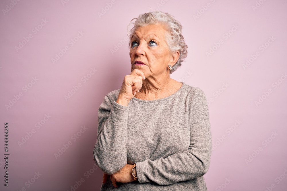 Senior beautiful woman wearing casual t-shirt standing over isolated pink background with hand on chin thinking about question, pensive expression. Smiling with thoughtful face. Doubt concept. Senior beautiful woman wearing casual t-shirt standing over isolated pink background with hand on chin thinking about question, pensive expression. Smiling with thoughtful face. Doubt concept.