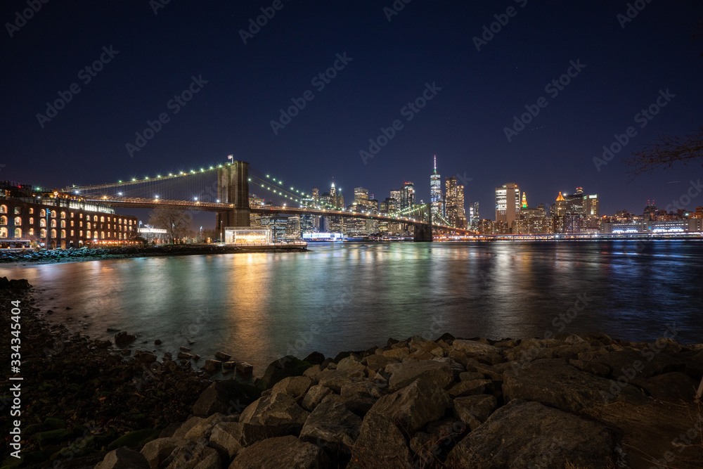 Panoramic Cityscape View of New York City at night with illuminated skyscrapers and bridges inside urban city center