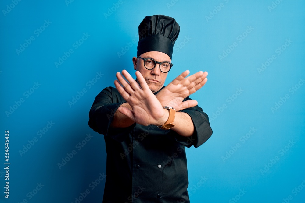 Middle age handsome grey-haired chef man wearing cooker uniform and hat Rejection expression crossing arms and palms doing negative sign, angry face Middle age handsome grey-haired chef man wearing cooker uniform and hat Rejection expression crossing arms and palms doing negative sign, angry face