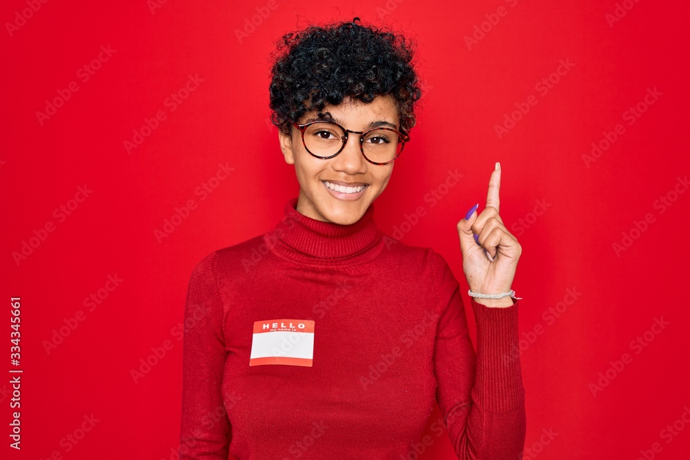 Young beautiful african american afro woman using sticker with presentation message surprised with an idea or question pointing finger with happy face, number one Young beautiful african american afro woman using sticker with presentation message surprised with an idea or question pointing finger with happy face, number one
