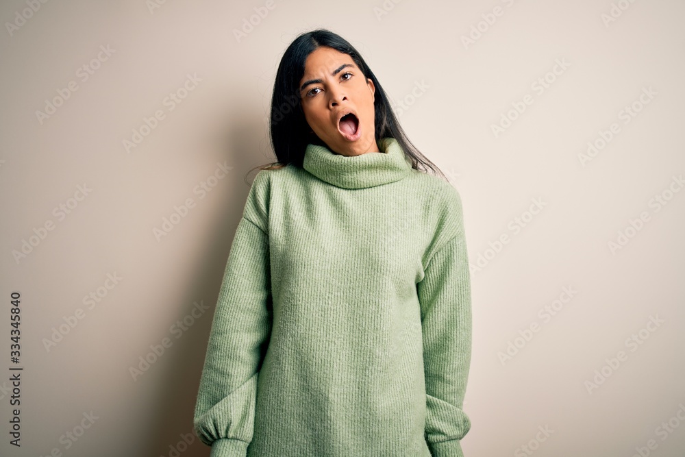 Young beautiful hispanic woman wearing green winter sweater over isolated background In shock face, looking skeptical and sarcastic, surprised with open mouth Young beautiful hispanic woman wearing green winter sweater over isolated background In shock face, looking skeptical and sarcastic, surprised with open mouth