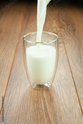 Protein breakfast milk from a jug in a glass on a wooden table splashes of milk.