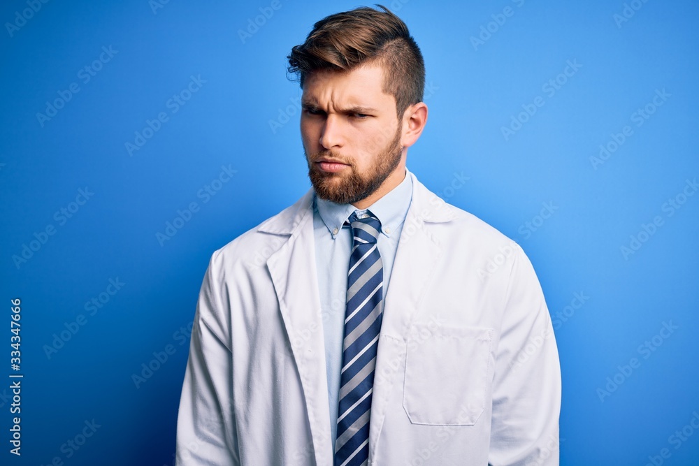 Young blond therapist man with beard and blue eyes wearing coat and tie over background skeptic and nervous, frowning upset because of problem. Negative person. Young blond therapist man with beard and blue eyes wearing coat and tie over background skeptic and nervous, frowning upset because of problem. Negative person.