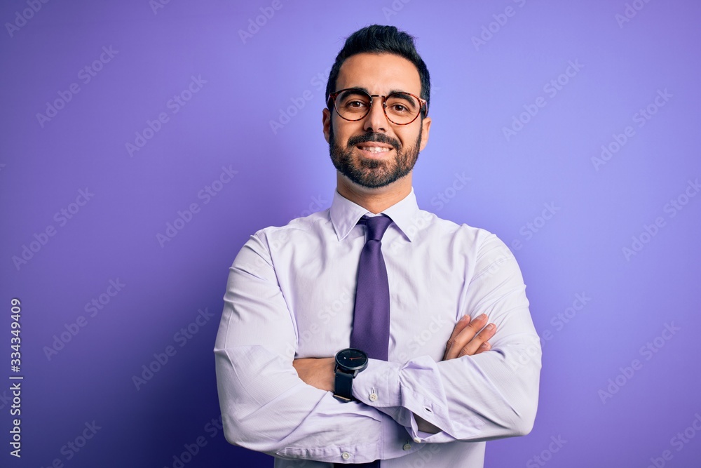 Handsome businessman with beard wearing casual tie and glasses over purple background happy face smiling with crossed arms looking at the camera. Positive person. Handsome businessman with beard wearing casual tie and glasses over purple background happy face smiling with crossed arms looking at the camera. Positive person.
