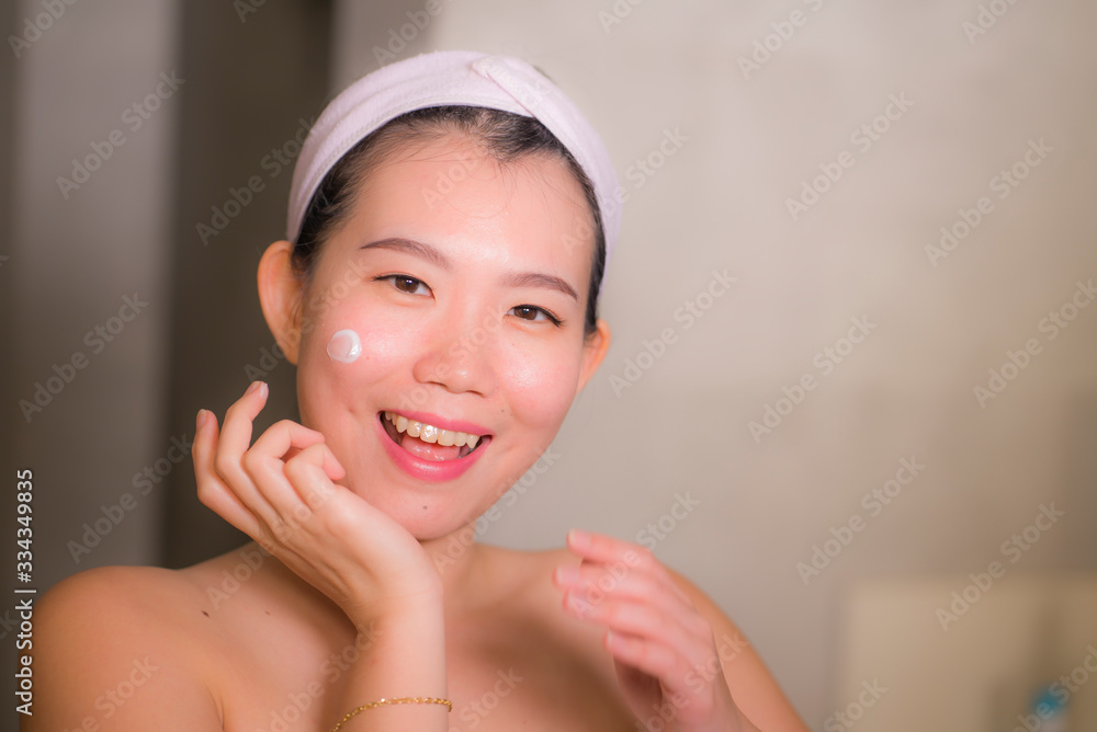 home lifestyle portrait of young happy and beautiful Asian Korean woman at bathroom mirror applying skin care moisturizer and anti-aging product in beauty and skincare concept home lifestyle portrait of young happy and beautiful Asian Korean woman at bathroom mirror applying skin care moisturizer and anti-aging product in beauty and skincare concept